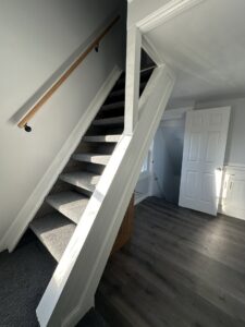 A newly renovated interior staircase with new carpet and flooring by Universal Builders LLC in New Haven, CT.