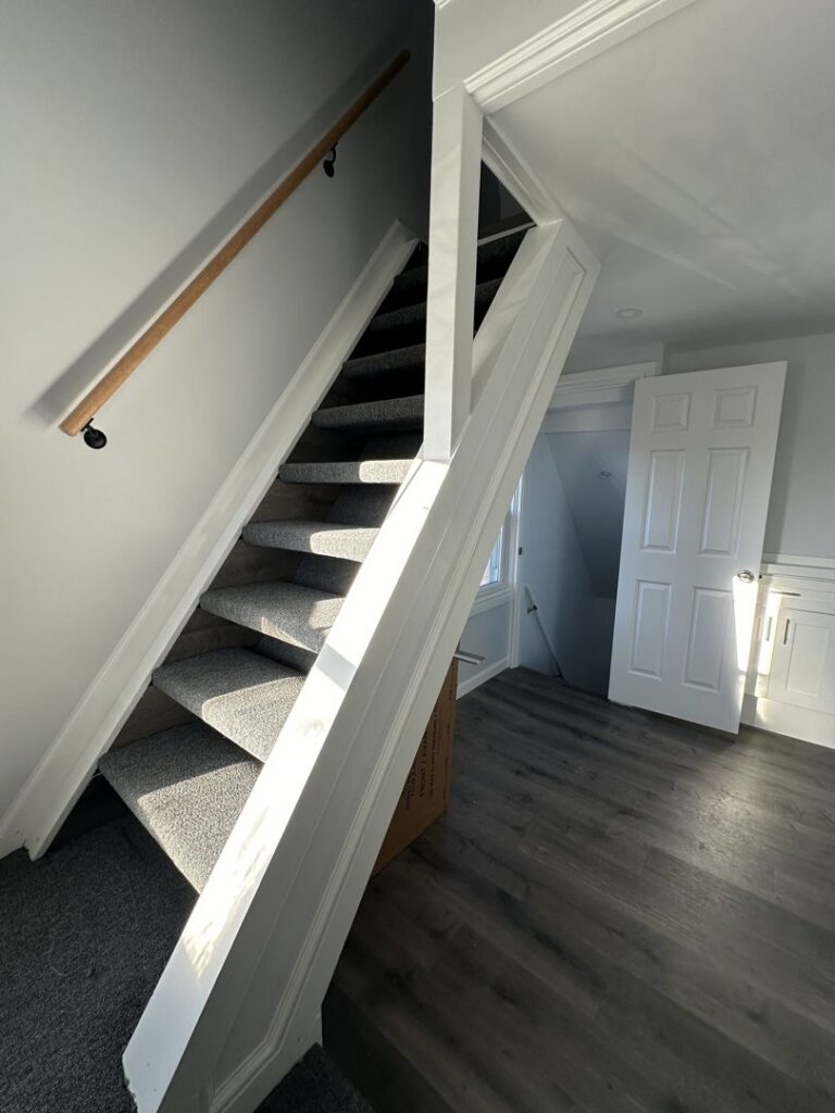 A newly renovated interior staircase with new carpet and flooring by Universal Builders LLC in New Haven, CT.