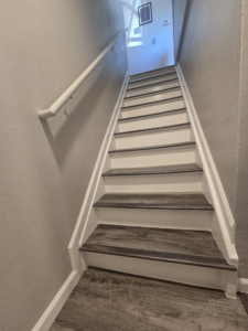 A newly installed staircase with wood-look treads and white risers by All In Remodeling Services LLC in Arvada, CO.