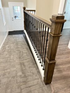 A newly installed staircase railing featuring elegant wood posts and black balusters by RW Contracting Phila, LLC in Philadelphia, PA.