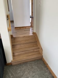 A newly installed staircase with wooden treads and a matching handrail by M Squared Construction LLC in Tonganoxie, KS.