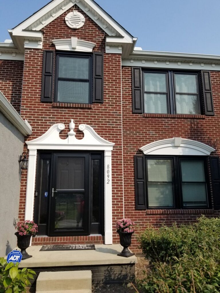 A newly installed black storm door and black shutters on a brick house by The Window Man of Ohio in Westerville, OH.