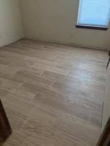 Newly installed wood-look tile flooring in a room by M&M Drywall and Construction in Enid, OK