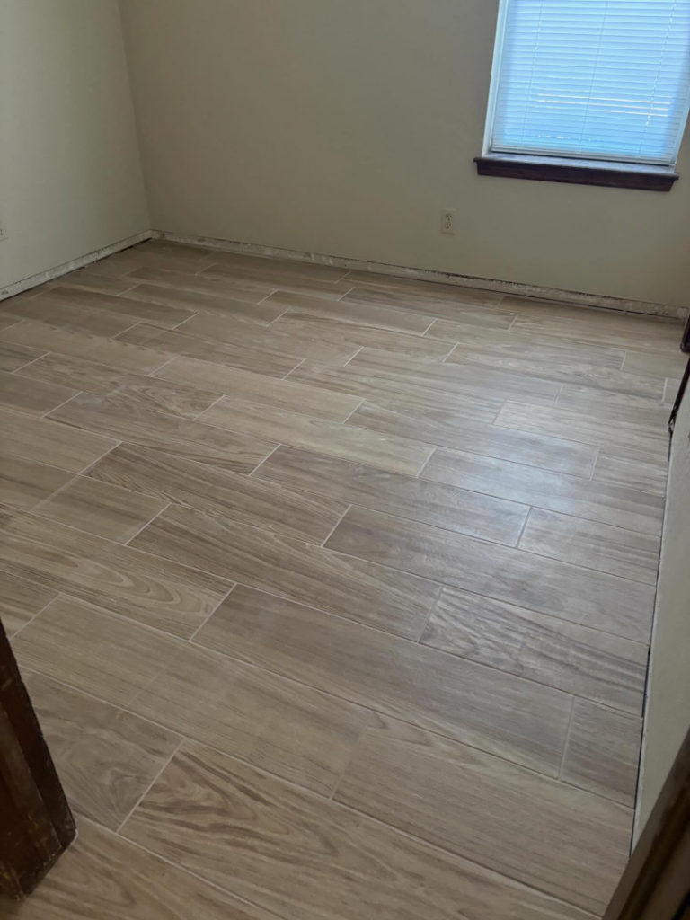 Newly installed wood-look tile flooring in a room by M&M Drywall and Construction in Enid, OK