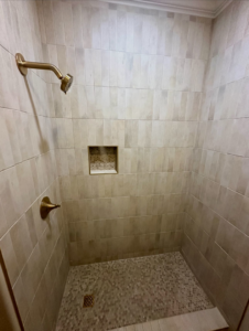 A newly tiled shower with modern fixtures installed by KMAC Construction in Youngsville, LA.