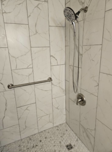 A newly tiled shower with a modern shower head, faucet, and grab bar installed by Tim's handyman service in Cherry Hill, NJ.