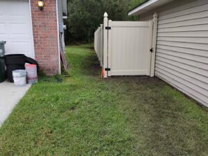A newly installed light-colored vinyl privacy fence with a functional gate by Fence & Deck Connection, Inc. in Savannah, GA.