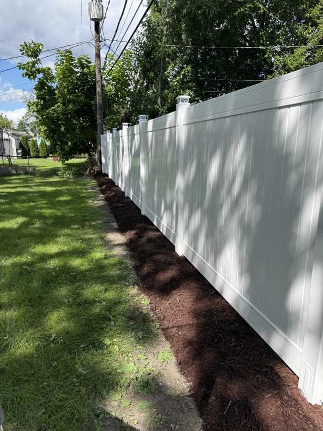A newly installed white vinyl fence with fresh mulch, completed by Villegas Remodeling & Handyman in Chicago, IL.