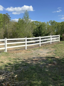 A newly installed white vinyl farm-style fence with wire mesh by Fence&Wash in Rock Hill, SC.