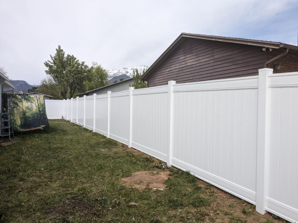 A newly installed white vinyl fence providing privacy and curb appeal in a backyard by Joel's Handyman in Ogden, UT.