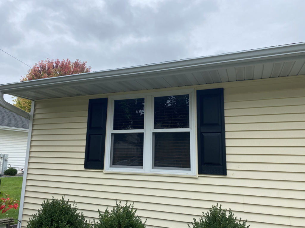 A newly installed window with black shutters on a house, a service by Urban Exteriors in Green Bay, WI.