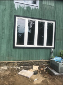 New window installation with black trim on a house exterior by JAC Home Improvement LLC in Danbury, CT.