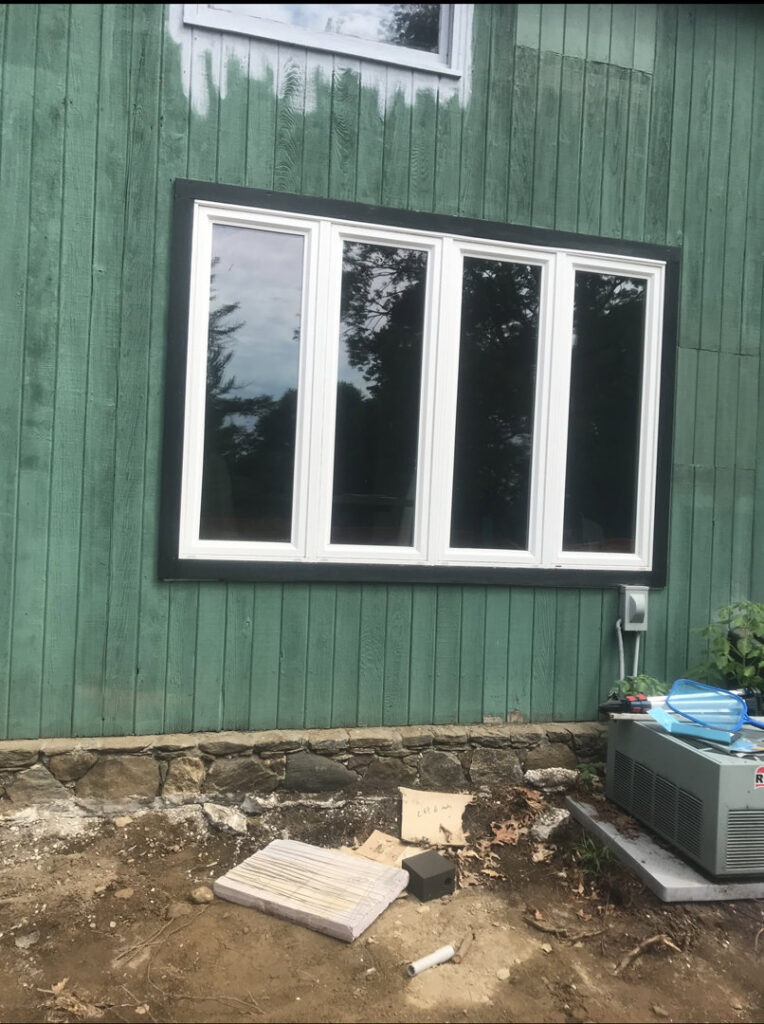 New window installation with black trim on a house exterior by JAC Home Improvement LLC in Danbury, CT.