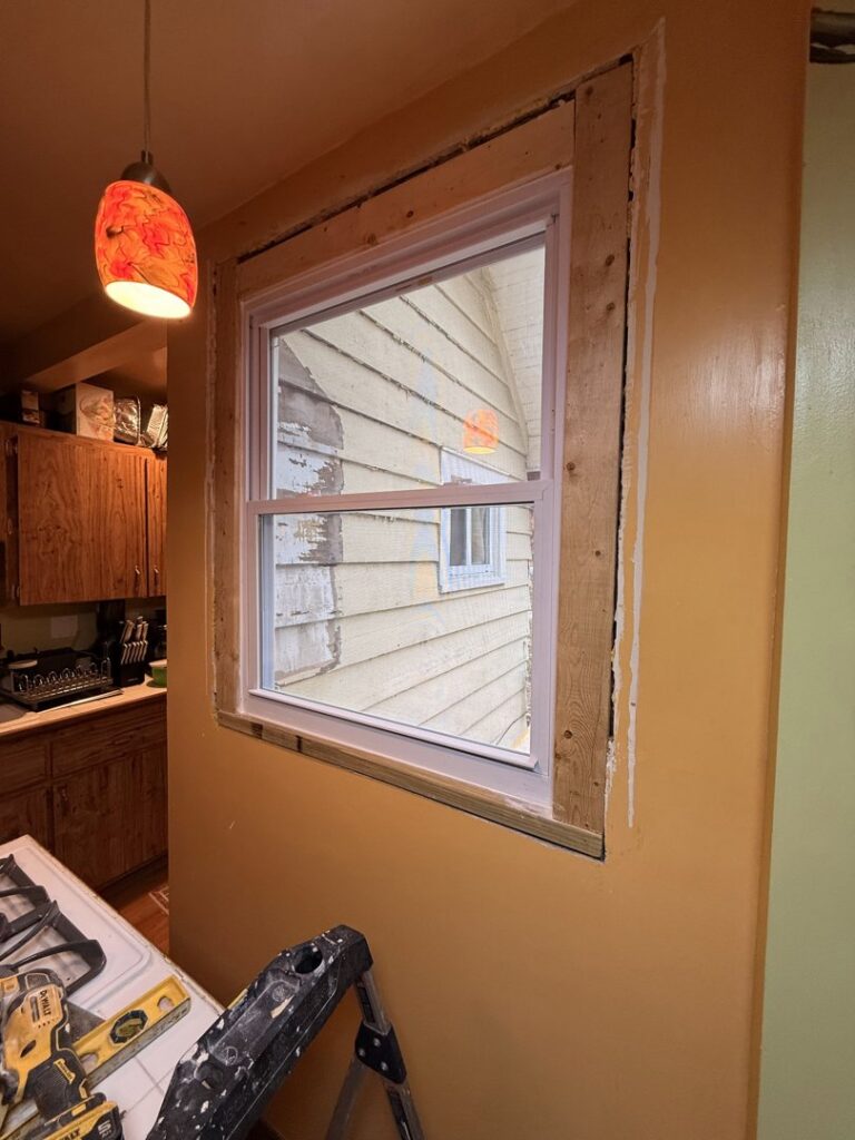 A new window installation in a kitchen with exposed framing, a service provided by Handy Fix Co. in Cleveland, OH.