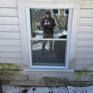 A newly installed window on a house exterior, reflecting the surroundings, by Noble Home Improvements in Edison, NJ.