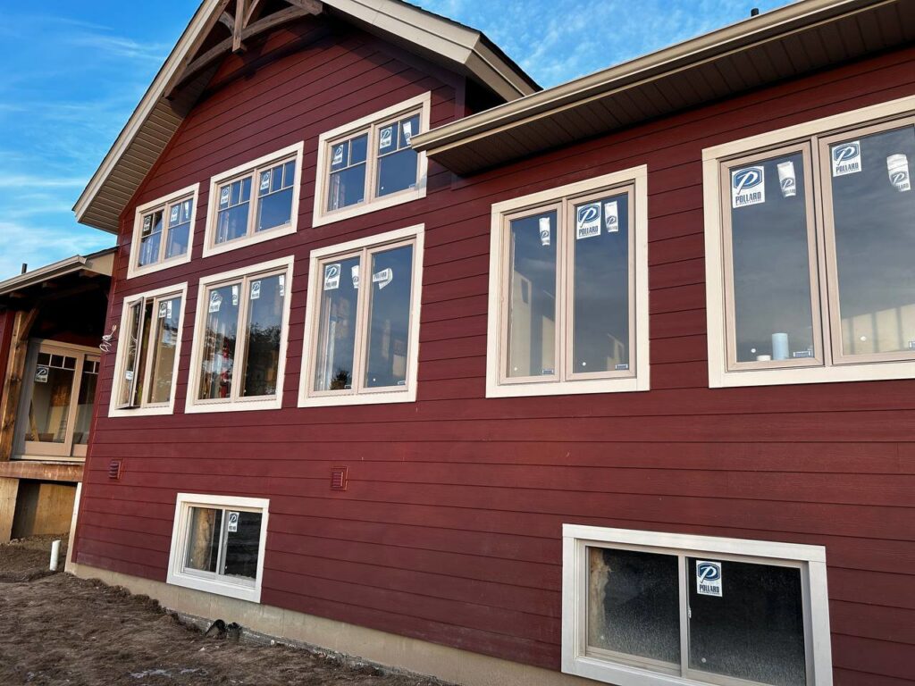 A red house with newly installed windows, showing a renovation project by Ideal Siding Memphis, TN