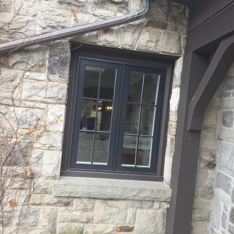 A newly installed black-framed window in a stone exterior, demonstrating Ember Works' general contractor work in Rochester, NY.