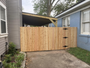 A newly installed wooden picket fence and gate between two homes by Shreveport Contractors in Shreveport, LA.