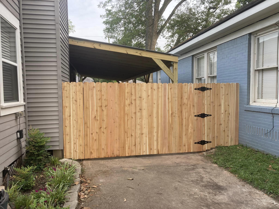 A newly installed wooden picket fence and gate between two homes by Shreveport Contractors in Shreveport, LA.