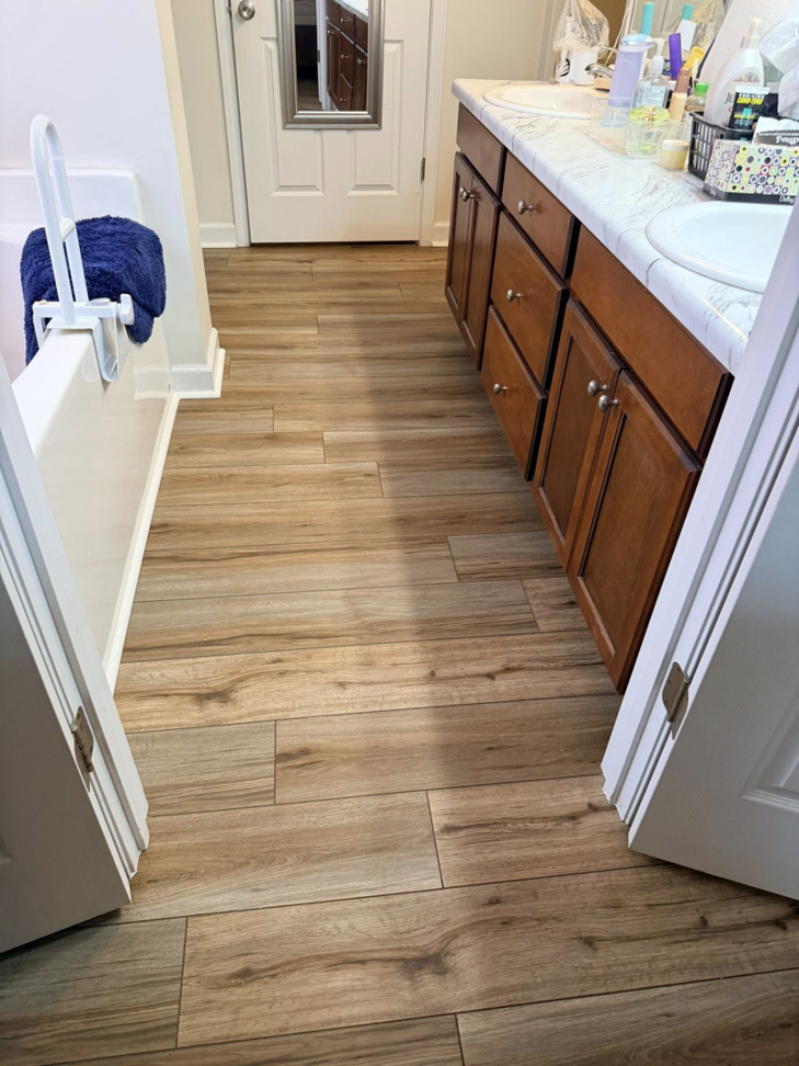 Stylish wood-look plank flooring installed in a bathroom with a vanity by Master Renovations LLC in Englewood, CO.