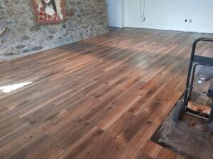 Newly installed wood-look tile flooring in a room with a stone accent wall, completed by Blas Home Remodeling LLC in New Castle, DE.