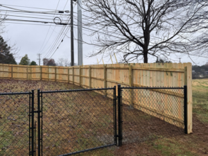 A newly installed wooden privacy fence with a black chain-link gate by Tim's Fencing in Knoxville, TN.
