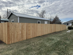 A newly installed long wooden privacy fence in a residential backyard by Bergmann Fencing Co. in Cedar Falls, IA.
