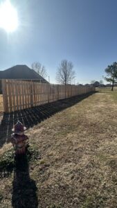 A newly installed wooden privacy fence extending across a property, completed by HomeFront Services LLC in Fayetteville, AR