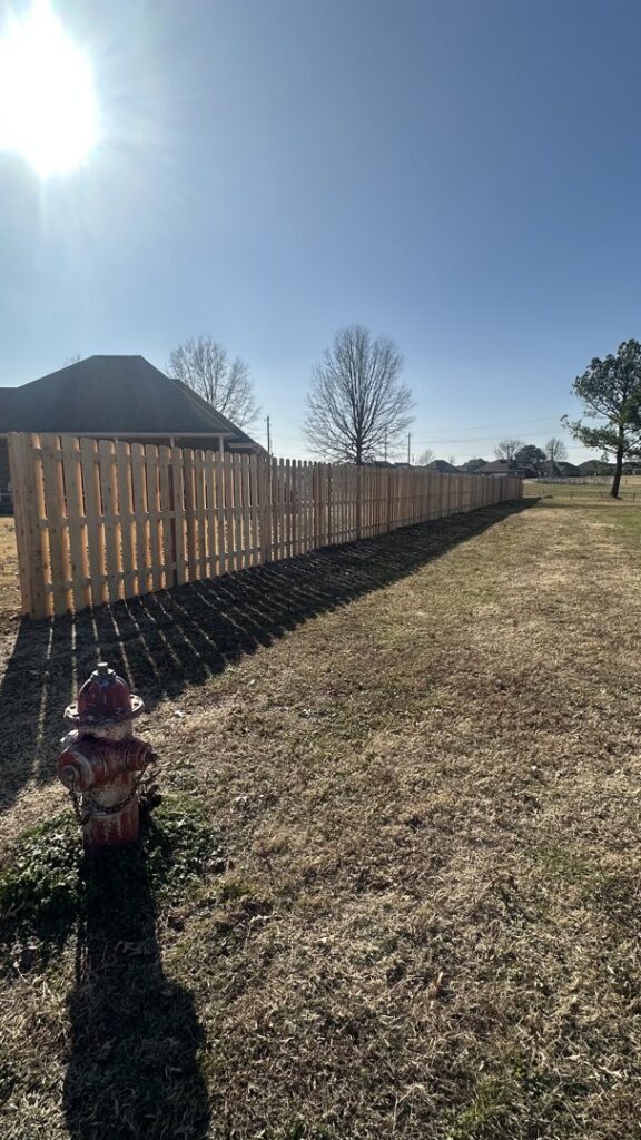 A newly installed wooden privacy fence extending across a property, completed by HomeFront Services LLC in Fayetteville, AR