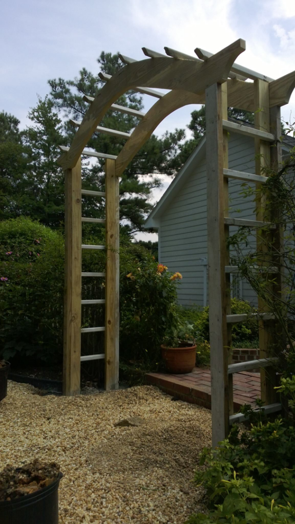 A newly installed wooden arbor in a garden by Randolph Residential Repair in Durham, NC.