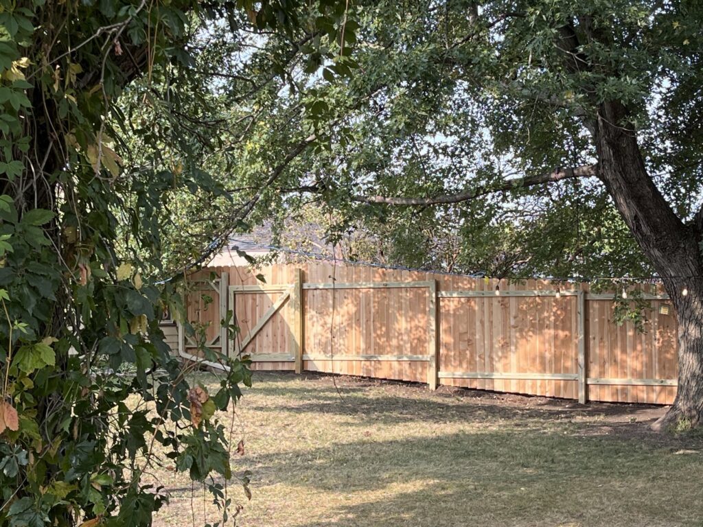 A newly installed wooden fence in a backyard, a professional service provided by Dakota Small Jobs in Sioux Falls, SD.