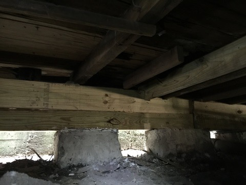 Newly installed wooden beams supporting a house foundation in New Orleans, LA, by Richard Earls Construction.