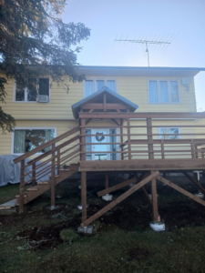 A newly constructed wooden deck with stairs leading to a house, built by RS handyman llc in Kenai, AK.