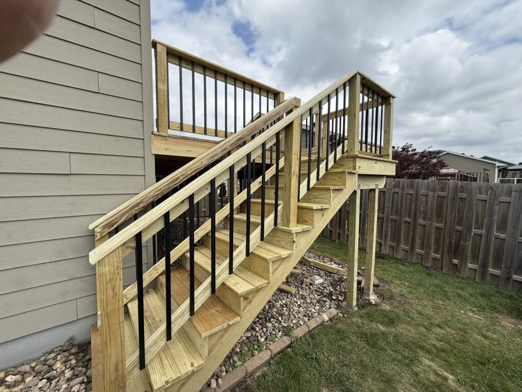 A newly constructed wooden deck with modern black metal railings and stairs by Watertown Handyman in Watertown, SD.