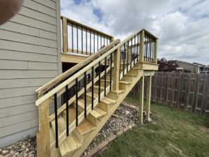 A newly constructed wooden deck with modern black metal railings and stairs by Watertown Handyman in Watertown, SD.