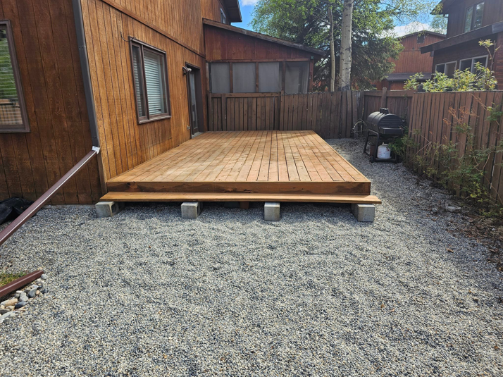 A newly constructed wooden deck on a gravel patio next to a house by Fairbanks Finest Handyman in Fairbanks, AK.