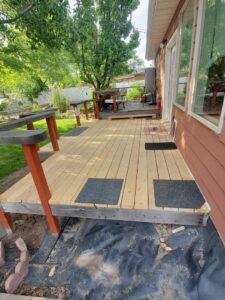 Newly constructed wooden deck in a backyard by Jonny Handyman Services in Roy, UT.