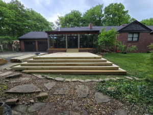A newly constructed wooden deck with multiple steps leading to a house by Mr. GreenJeans in Indianapolis, IN.