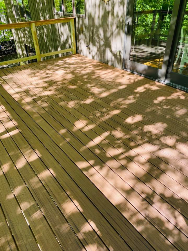A newly installed wooden deck with railing by Mohawk Home Improvement of Syracuse LLC in Syracuse, NY.
