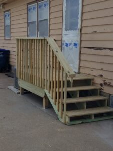 A newly constructed wooden deck and stairs leading to a house by Rosewalls Handyman & Remodeling in Des Moines, IA.