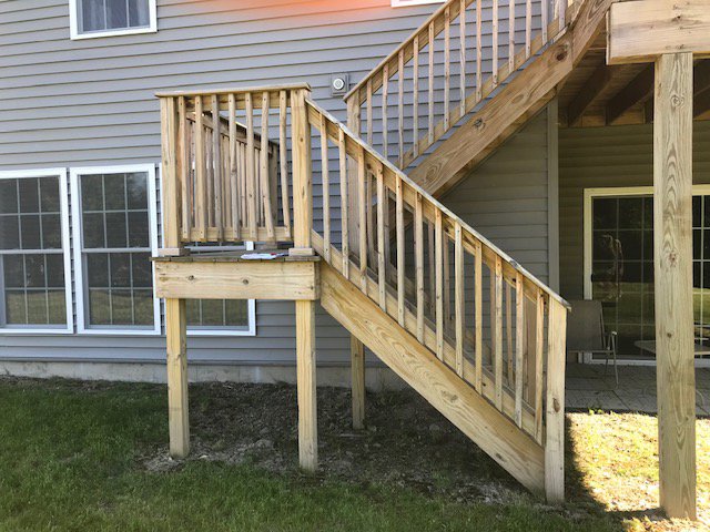 A newly constructed wooden deck and stairs leading to a house exterior by Carl Gardner Contracting in Syracuse, NY.
