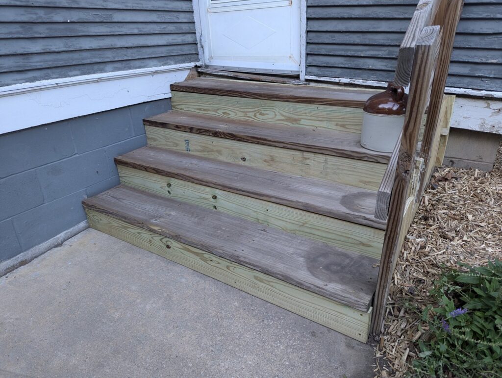 Newly installed wooden steps leading to a house entryway, a completed project by Folmar's Handyman & Remodeling in Lincoln, NE.