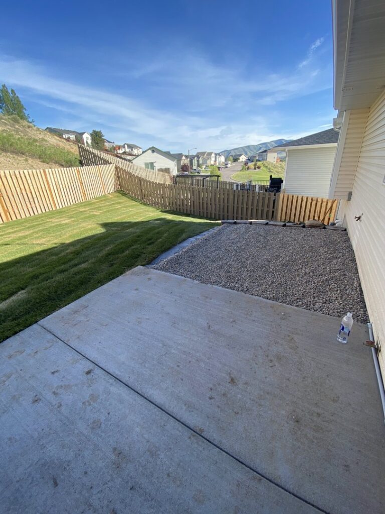 Newly installed wooden fence and gravel landscaping in a backyard, a service provided by No Delay SVCS in Pocatello, ID.