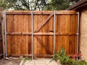 A newly installed wooden fence with a gate, showcasing exterior work by Brewer Builds in Fort Worth, TX.