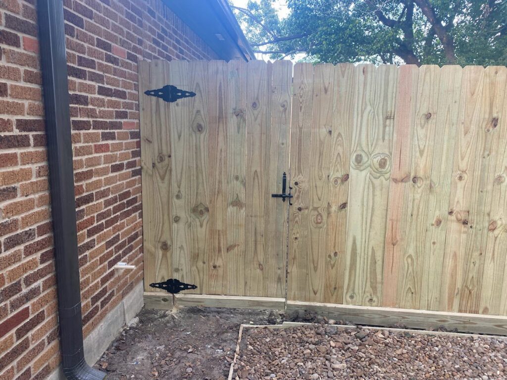 Newly installed wooden fence and gate next to a brick house by SRP construction in Houston, TX