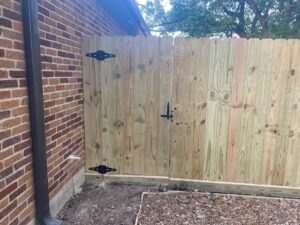 Newly installed wooden fence and gate next to a brick house by SRP construction in Houston, TX