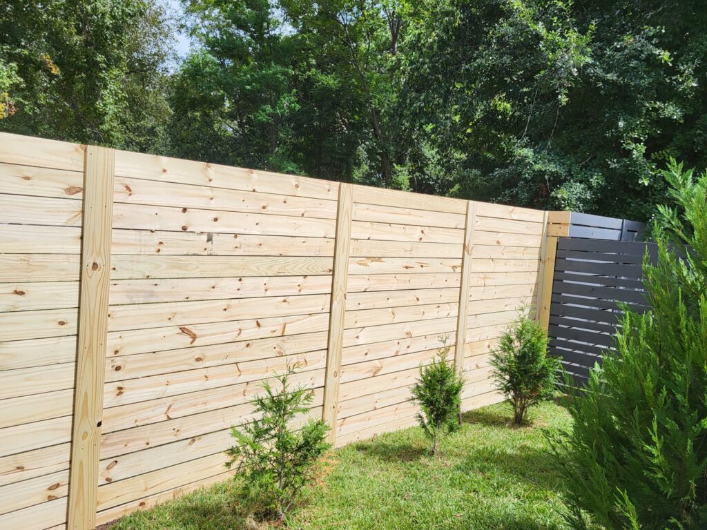 Newly installed wooden fence in a backyard by Gladiator Flooring LLC, a handyman service in Summerville, SC.