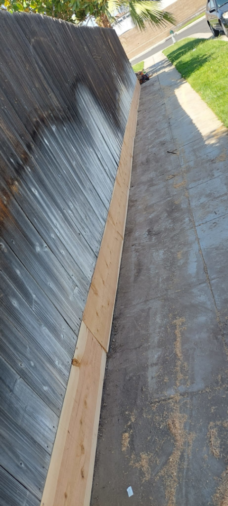 Newly installed wooden planks repairing an old fence, showcasing work by Montano's Handyman in Fresno, CA