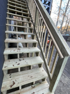 Newly installed wooden outdoor stairs with a handrail by Shepard Remodeling in Huntsville, AL.
