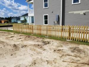A newly installed wooden picket fence in a residential area by Frontline Fencing LLC in Summerville, SC.